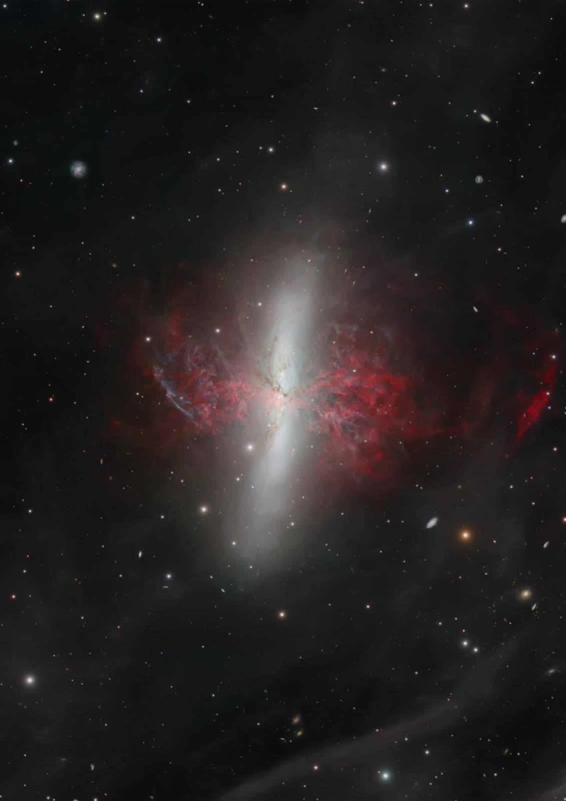 M82, the Cigar Galaxy, an edge-on spiral galaxy with red hydrogen filaments above and below its disc
