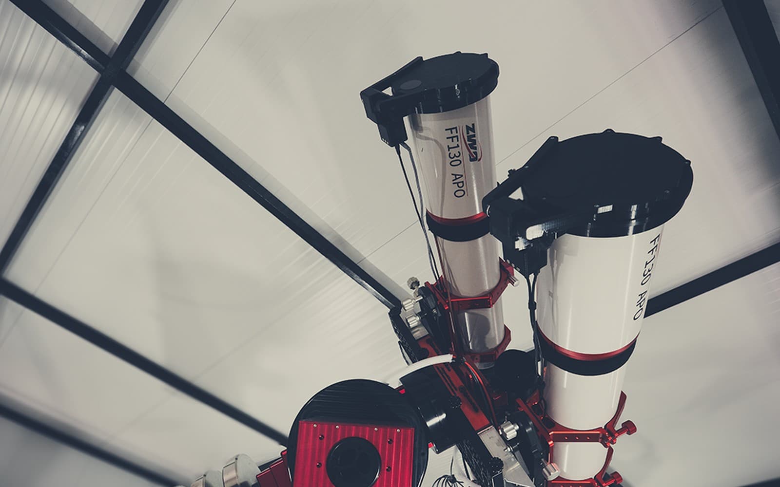 The twin FF130s parked side by side on their mount under a roll-off roof, photographed at the Practical Astronomy Show